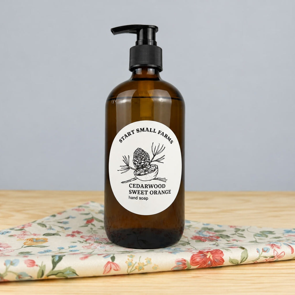 A Start Small Farms Cedarwood Sweet Orange hand soap in an amber glass pump bottle