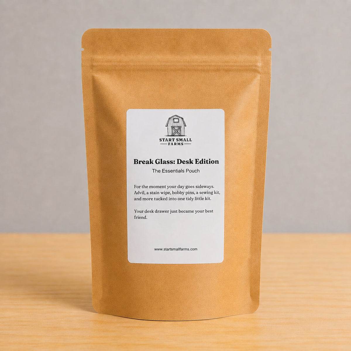 A kraft paper stand-up pouch labeled 'Start Small Farms Break Glass: Desk Edition' standing on a light wood surface against a neutral gray background.