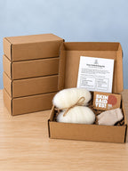 Five Felted Wool Soap DIY Kit boxes, four stacked closed and one open showing a bundle of cream wool roving tied with twine, a boxed bar of soap, a folded cloth and the kit card standing in the lid