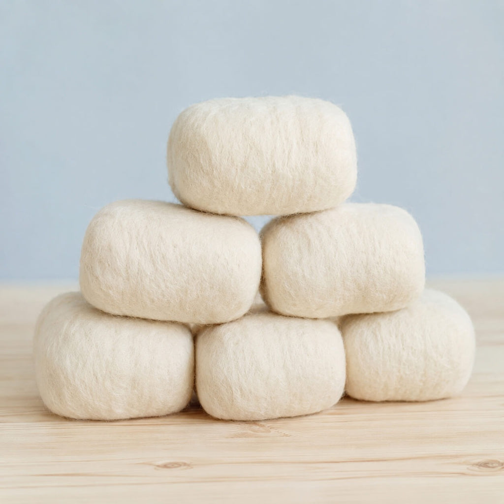 Six finished bars in cream wool jackets stacked in a pyramid on a pine table