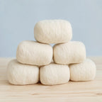 Six finished bars in cream wool jackets stacked in a pyramid on a pine table