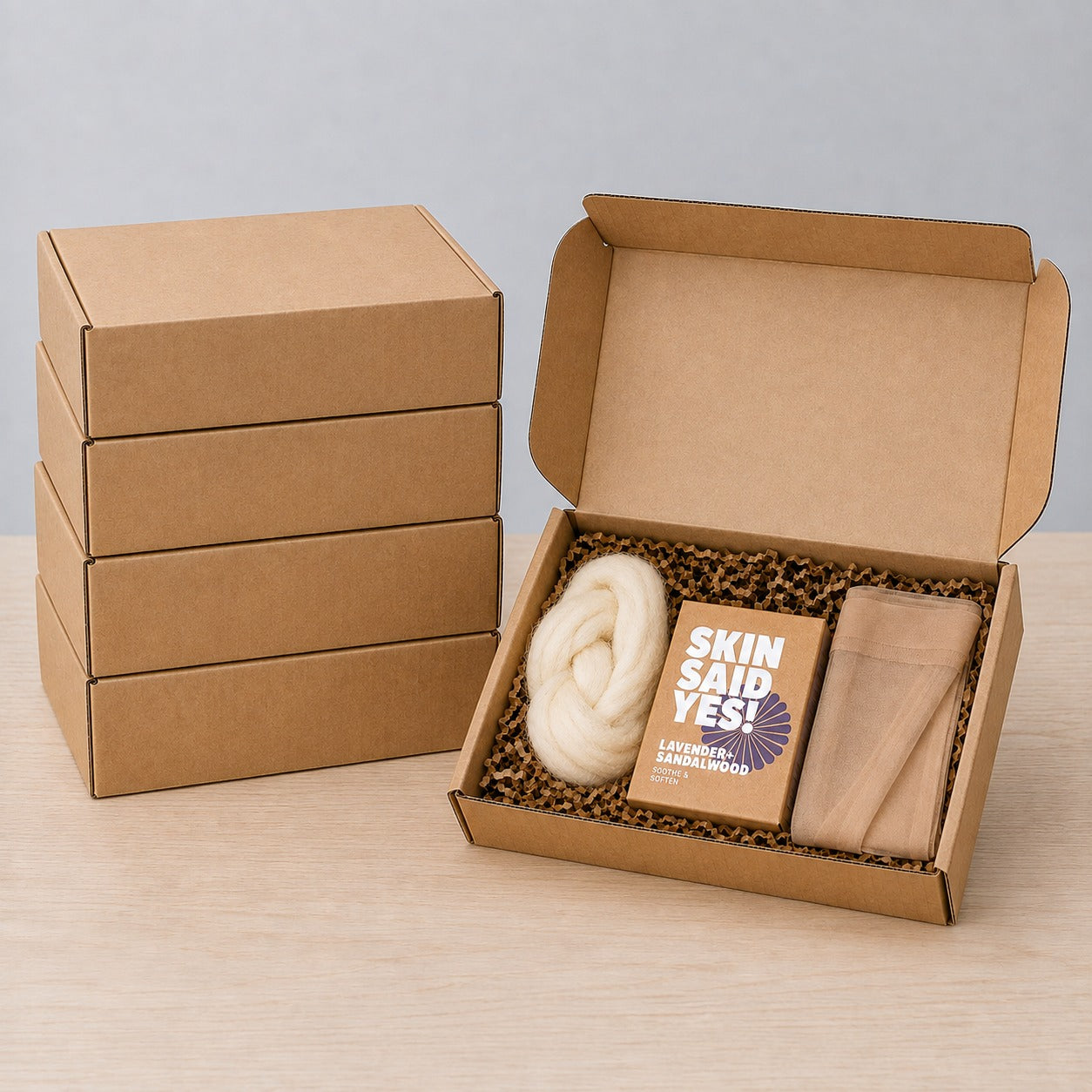 Five Felted Wool Soap DIY Kit boxes, four stacked closed and one open showing a braid of cream wool roving, a boxed bar of soap and a folded nylon stocking
