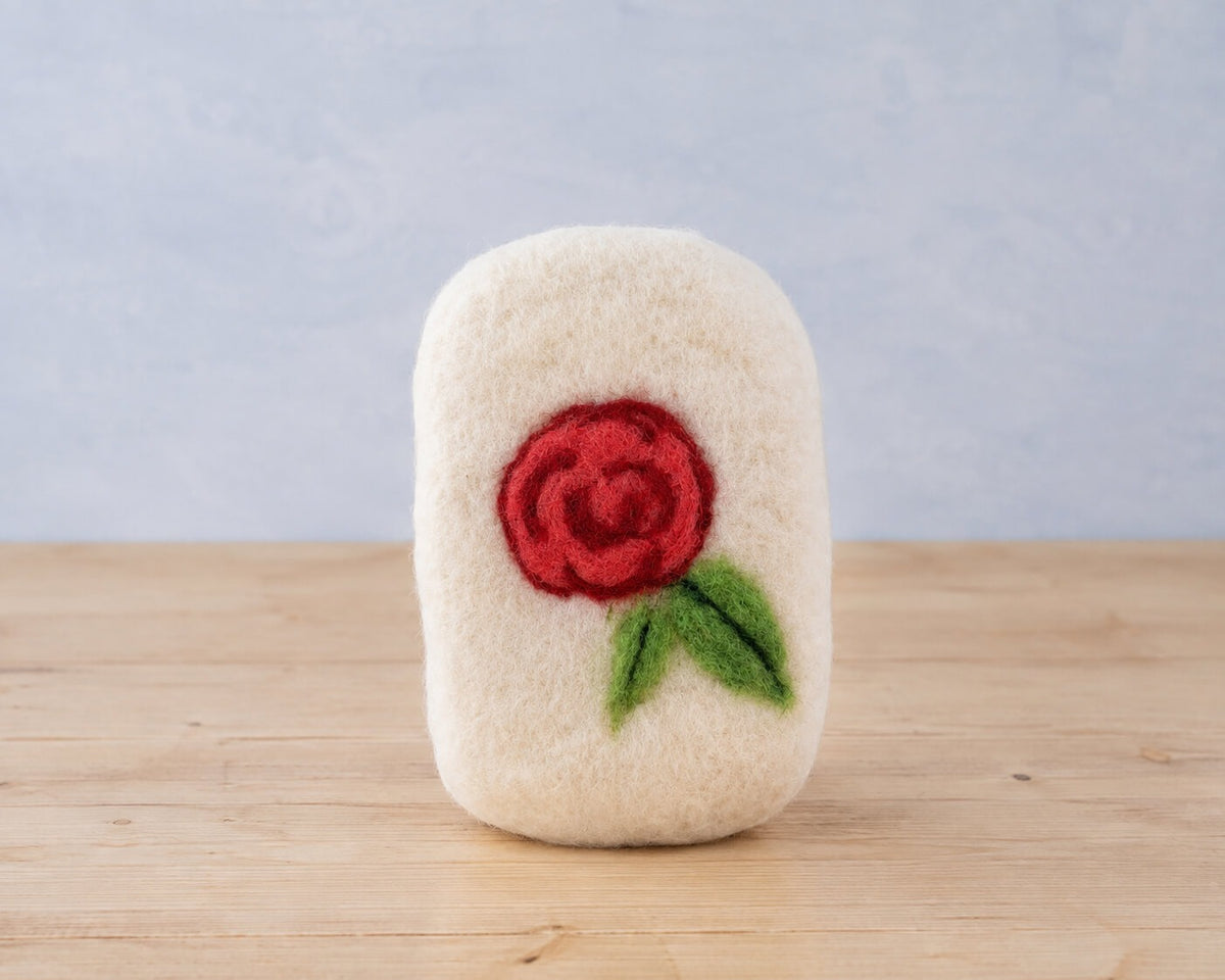 A finished felted bar with a red needle felted rose and two green leaves worked into the wool
