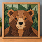 A chunky brown bear kinusaiga piece in a natural wood frame, standing on a wooden shelf against a blue-grey wall: a round geometric bear face in tan, caramel and chocolate brown fabrics, with a cream muzzle, black nose and dark inner ears, in front of pine trees pieced in five shades of green.
