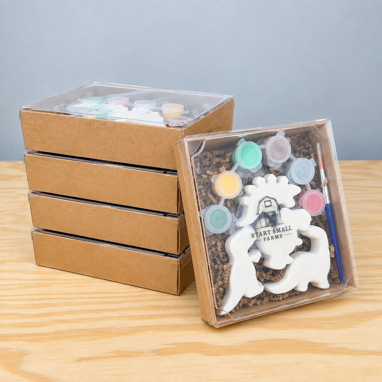 Five Make It Mine Magnet Multipack kits, four stacked closed and one open showing plaster animals, six paint pots and a brush under a clear lid