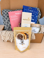 The Start Small Farms bath soak pouch standing in front of the open box, dried orange and lemon slices showing through the window above the salts.
