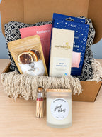 The Start Small Farms Just Vibes candle in a frosted glass jar and a corked vial of wooden matches in front of the open box.