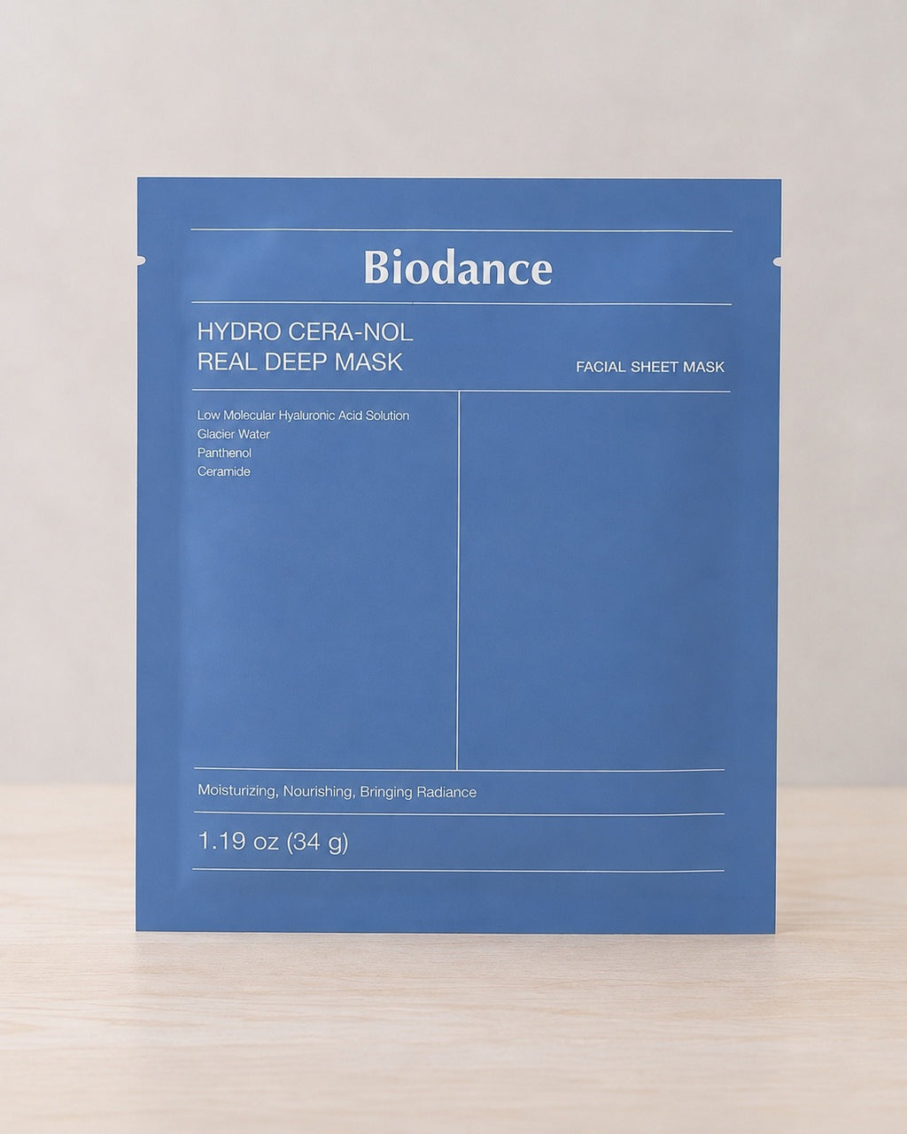The Biodance Hydro Cera-Nol Real Deep Mask sheet mask in its blue foil sachet, standing on pale wood
