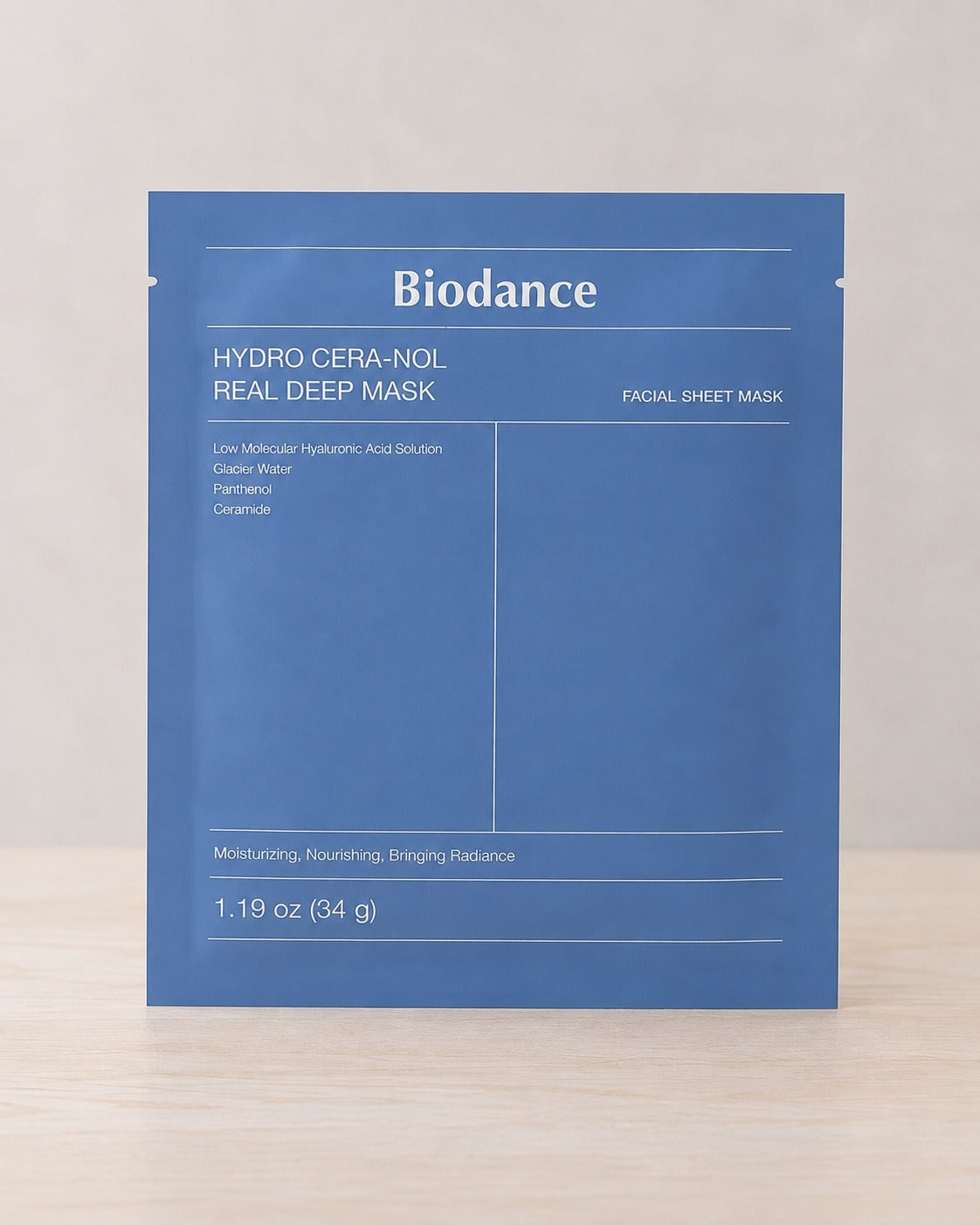 The Biodance Hydro Cera-Nol Real Deep Mask sheet mask in its blue foil sachet, standing on pale wood