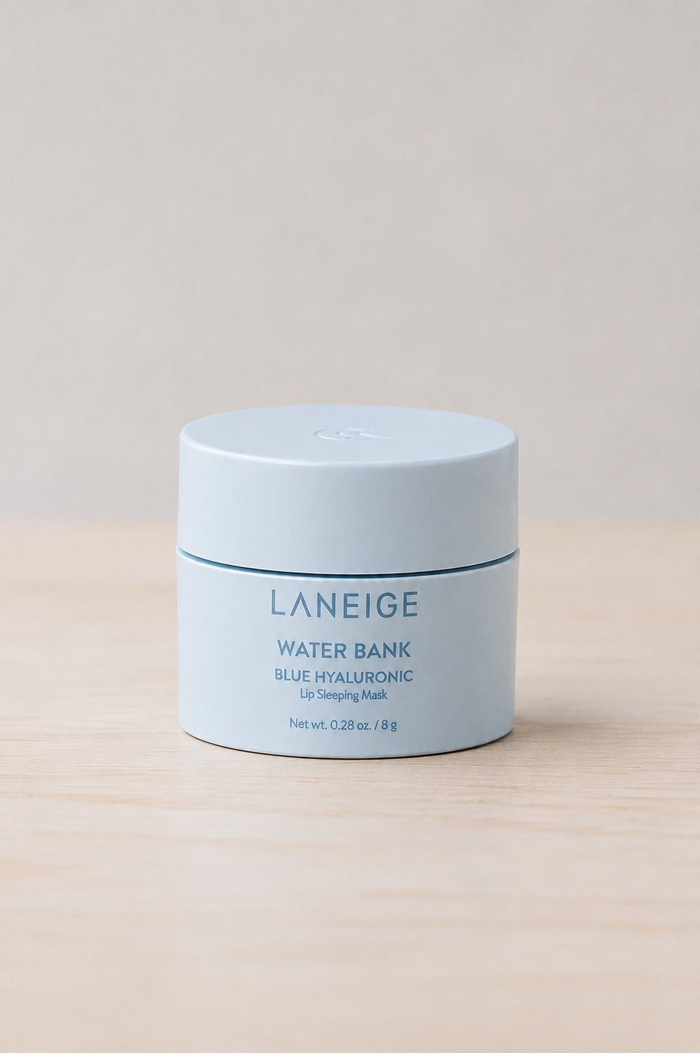 The Laneige Water Bank Blue Hyaluronic lip sleeping mask in its pale blue jar, on pale wood