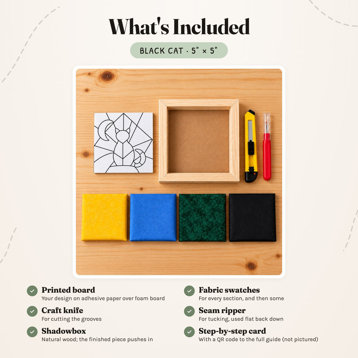 What's included in the Black Cat kit, laid out on a wood table: the printed board, fabric swatches, a craft knife, a seam ripper and the natural wood shadowbox. The step-by-step card is not pictured.