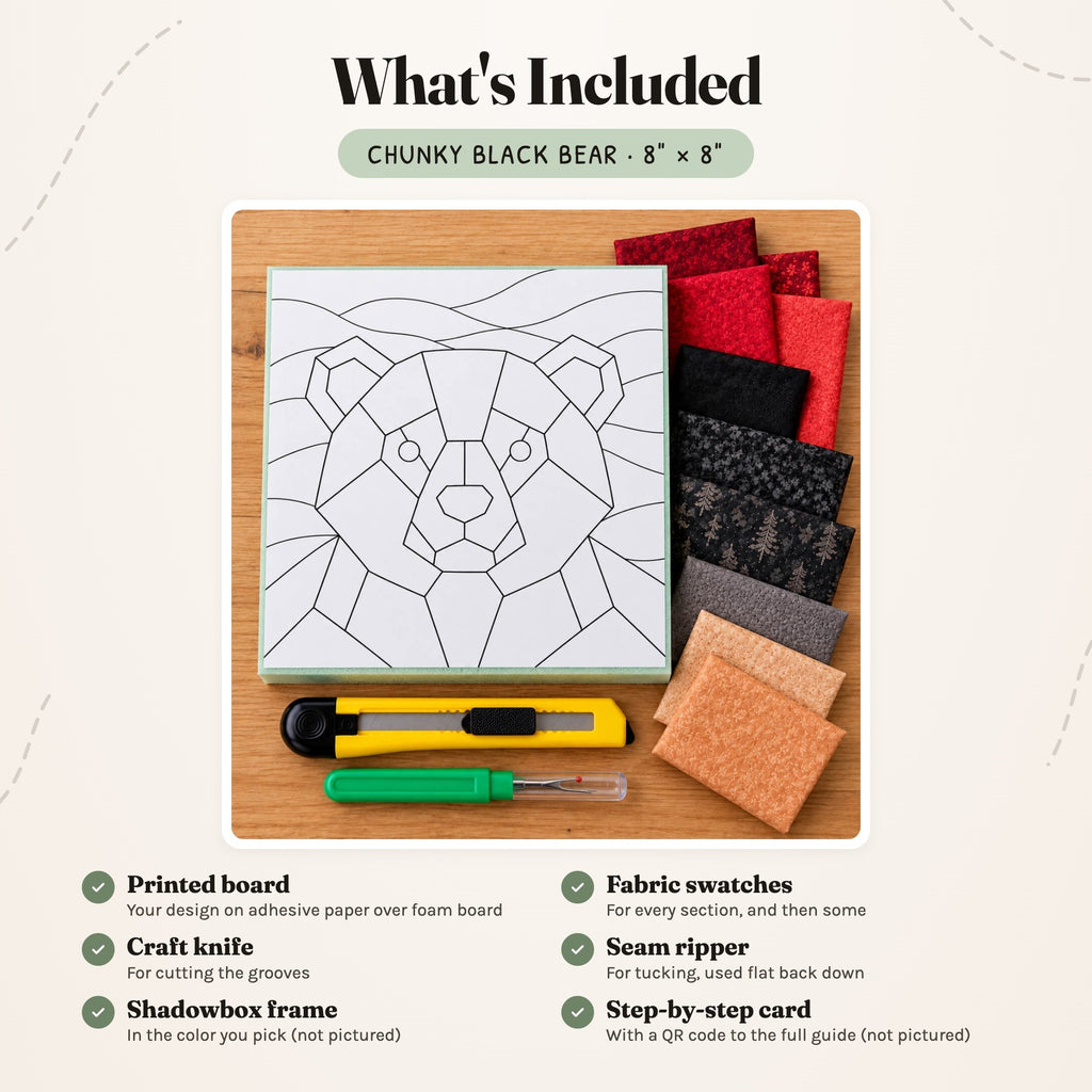What's included in the Chunky Black Bear kit, laid out on a wood table: the printed bear board, fabric swatches in reds, blacks, greys and tan, a craft knife and a seam ripper. The shadowbox frame and the step-by-step card are not pictured.