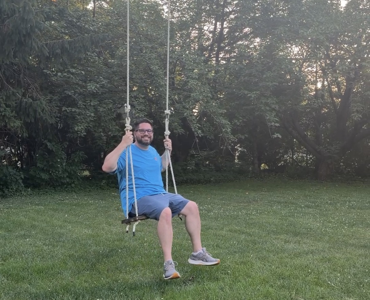 Jason mid-swing on a tree swing during a farm property tour.